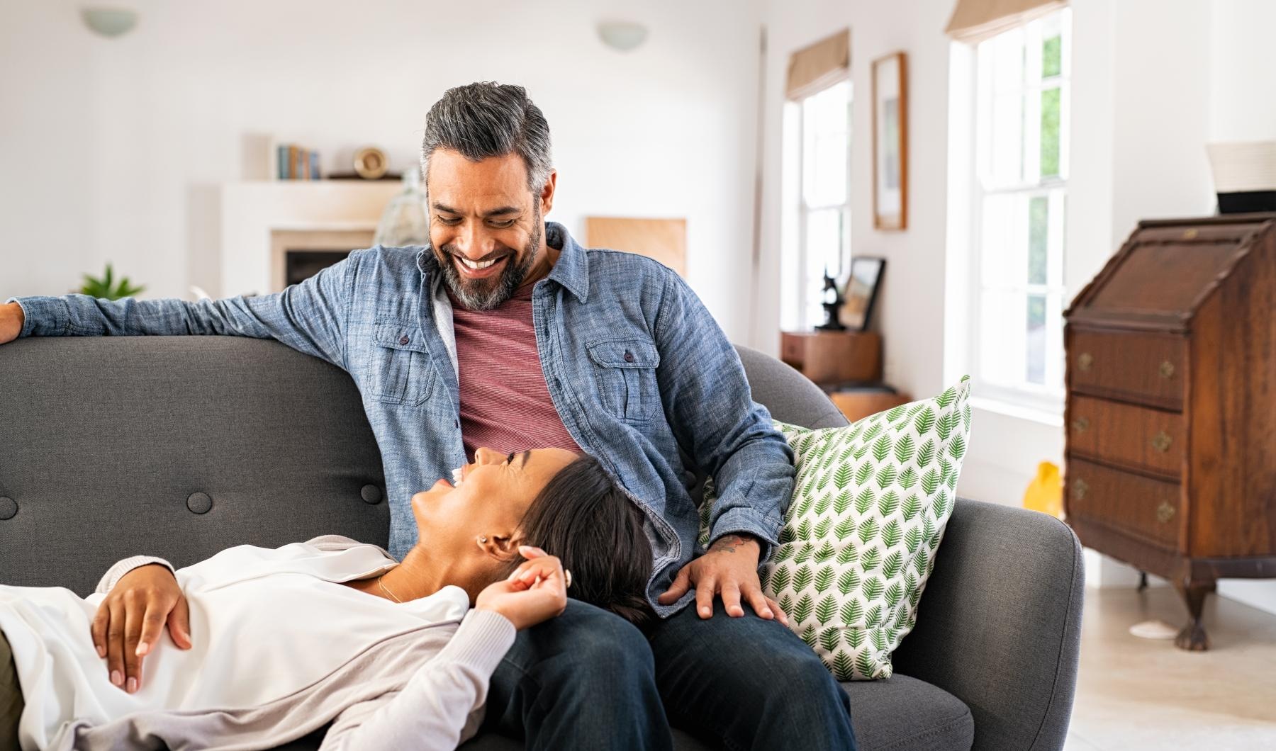 Settle into comfort at Grandea Bellfort a couple embracing on a grey couch in a bright room