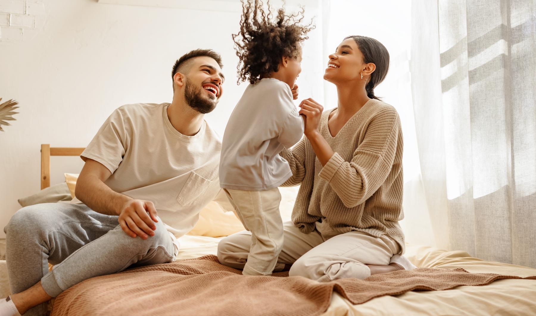 Sleep in style a man and woman sitting on a bed with a child on his lap